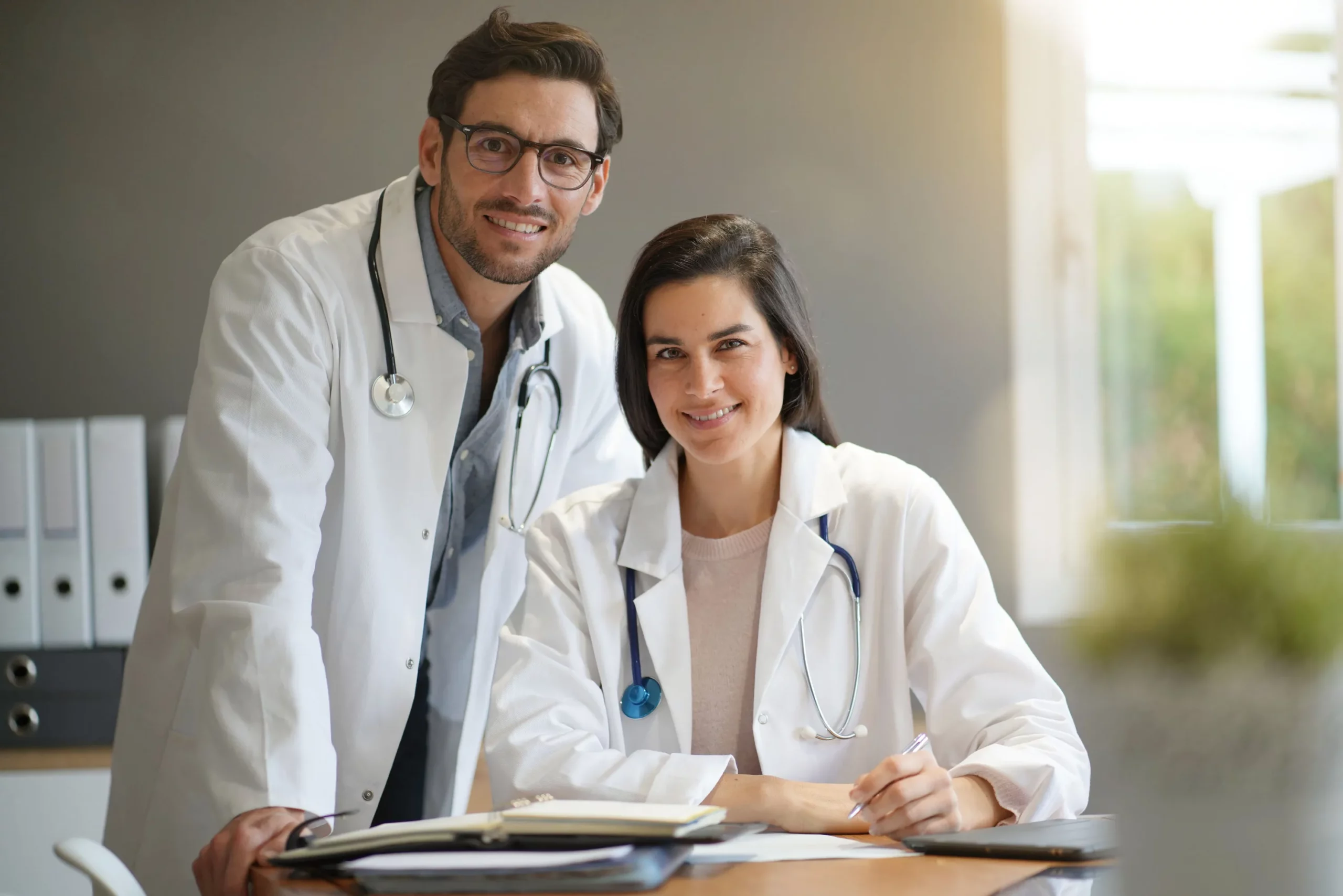 A male and female doctor smiling and posing for a photo