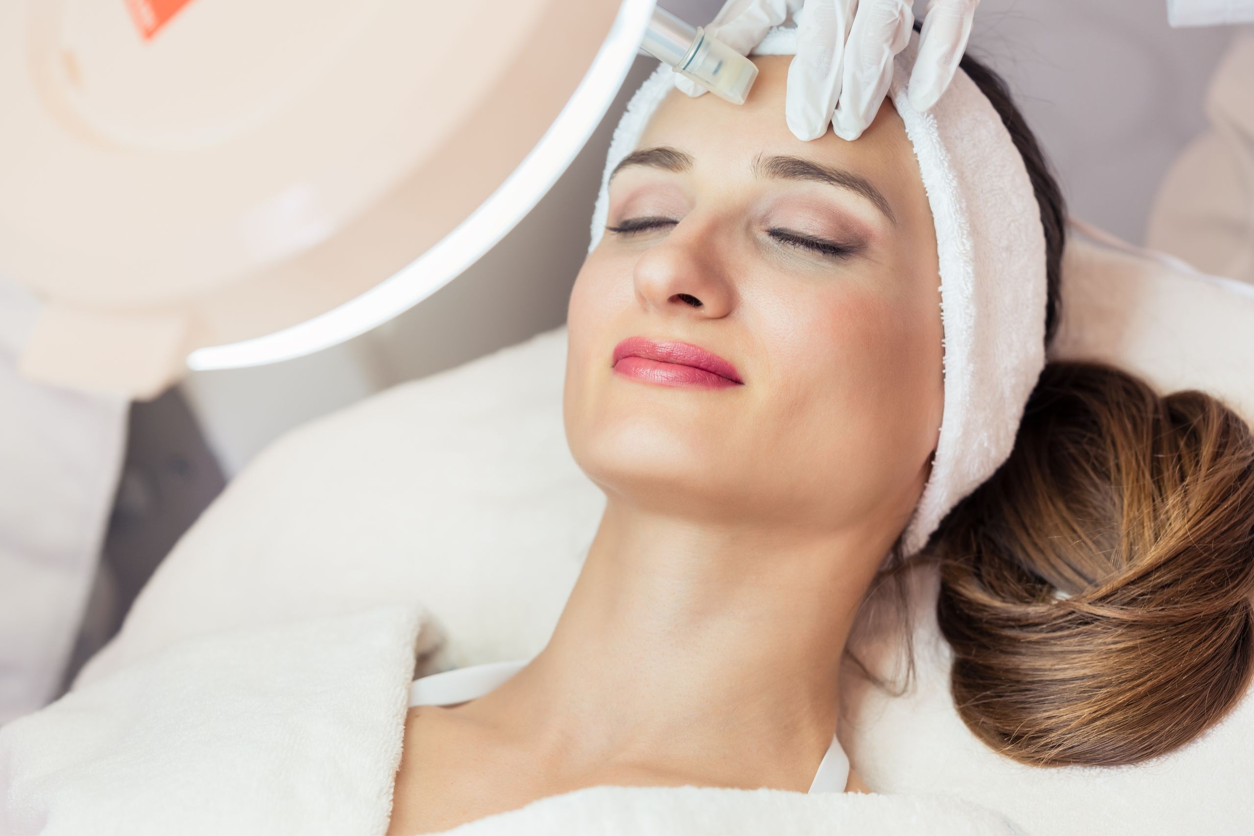 A close-up of a woman receiving a facial aesthetic treatment